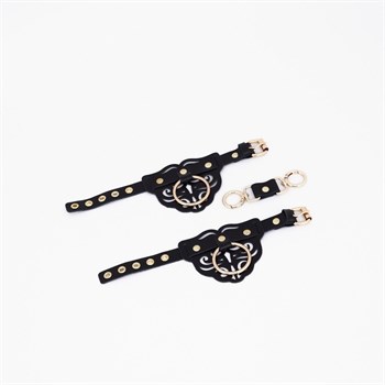 {{photo.Alt || photo.Description || 'Черные кожаные наручники с клепками, кольцами и золотистой фурнитурой'}}